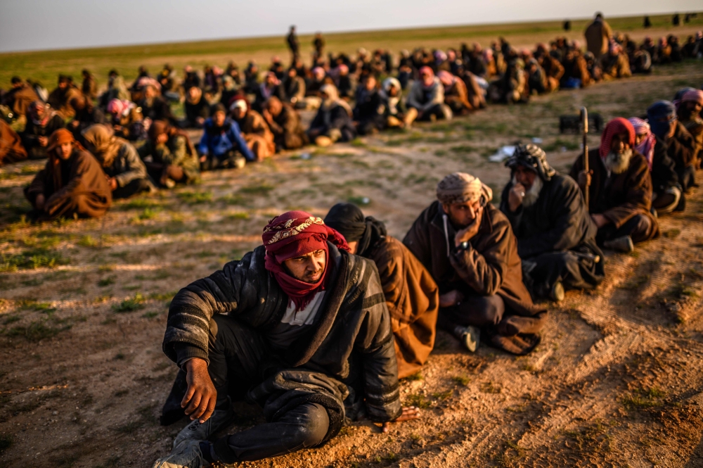 Men suspected of being Islamic State (IS) fightrs wait to be searched by members of the Kurdish-led Syrian Democratic Forces (SDF) after leaving the IS group's last holdout of Baghouz in Syria's northern Deir Ezzor province, on February 22, 2019. / AFP / 