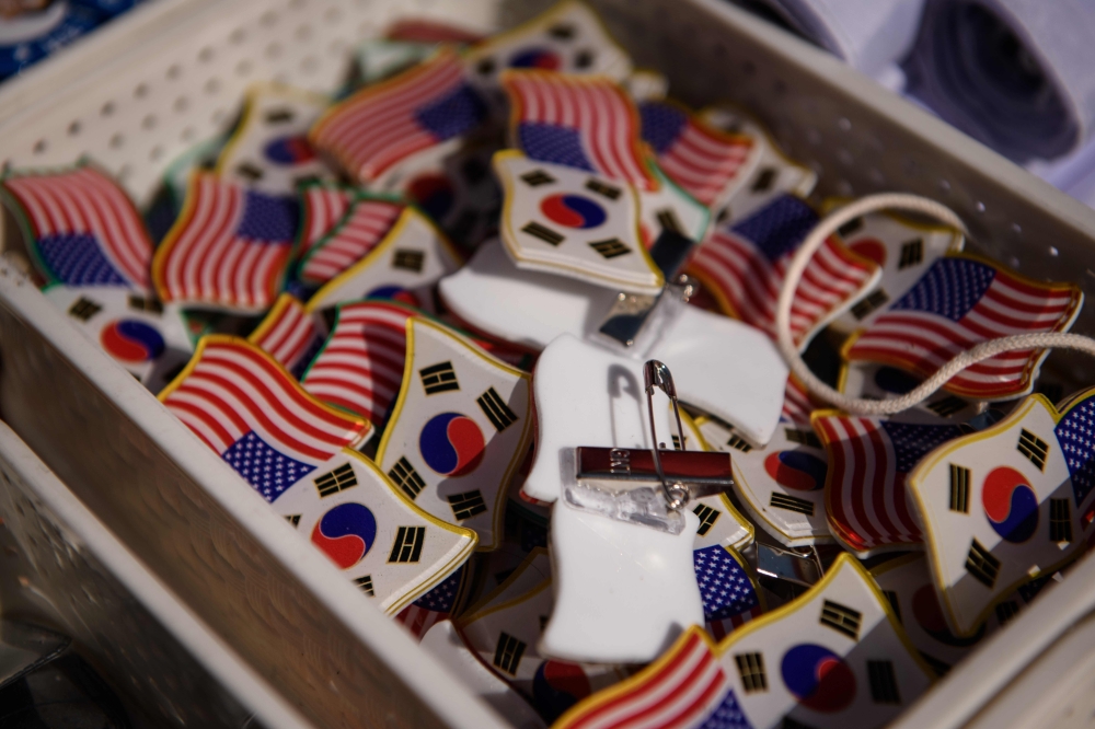 Pin badges are displayed as conservative anti-North Korea, pro-US activists march through central Seoul on February 23, 2019. / AFP / Ed JONES 