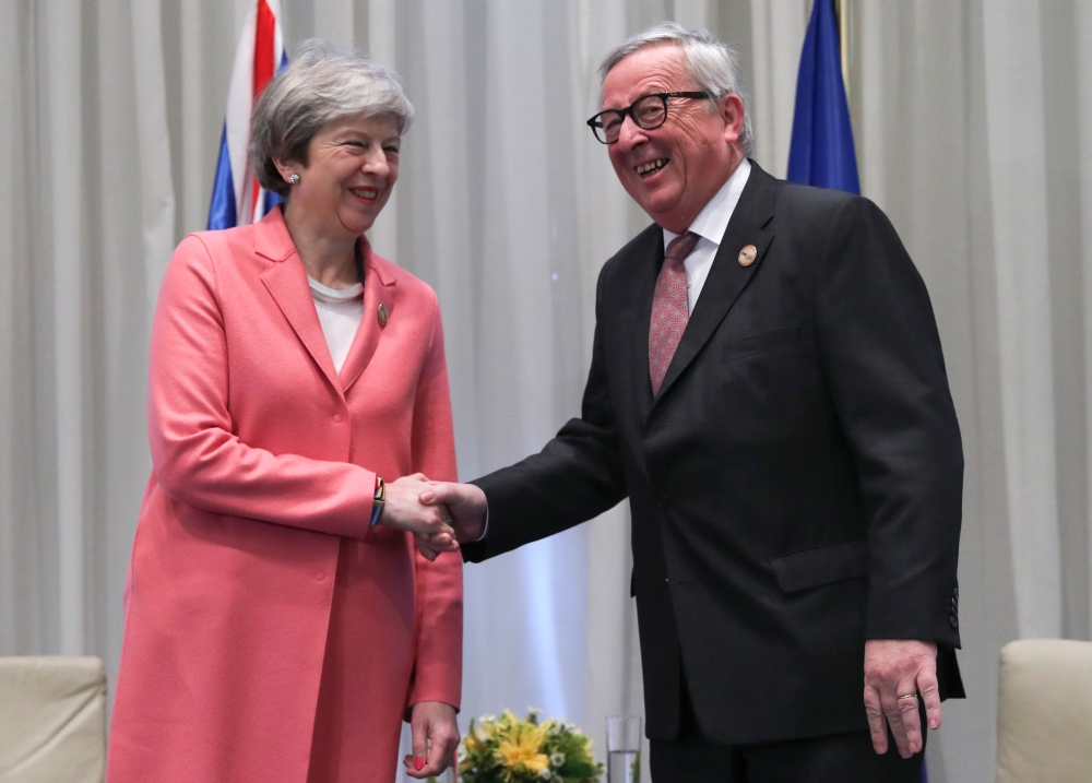 Britain's Prime Minister Theresa May (L) greets the European Commission President Jean-Claude Juncker during a meeting on the sidelines of the first joint European Union and Arab League summit at the International Congress Centre in the Egyptian Red Sea r