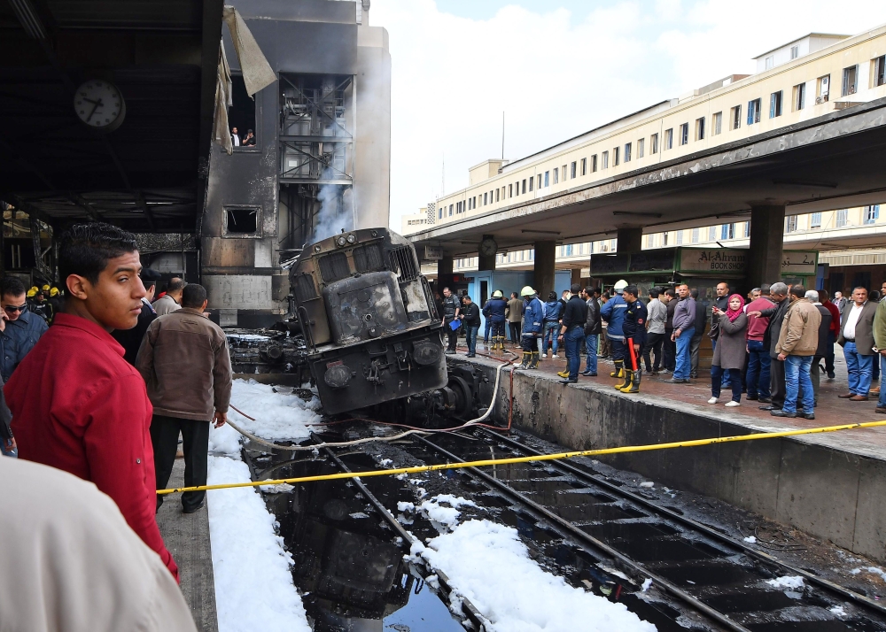 Fire fighters and onlookers gather at the scene of a fiery train crash at the Egyptian capital Cairo's main railway station on February 27, 2019.  AFP / Ahmad Hassan