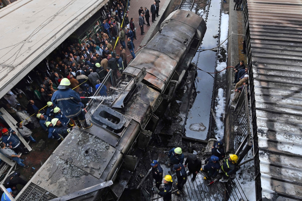 Firefighters and onlookers gather at the scene of a fiery train crash at the Egyptian capital Cairo's main railway station on February 27, 2019.  AFP / STRINGER