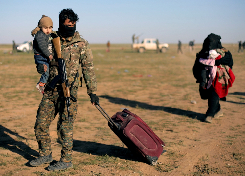 A fighter from Syrian Democratic Forces (SDF) holds a baby near the village of Baghouz, Deir Al Zor province, Syria March 1, 2019. REUTERS/Rodi Said 
