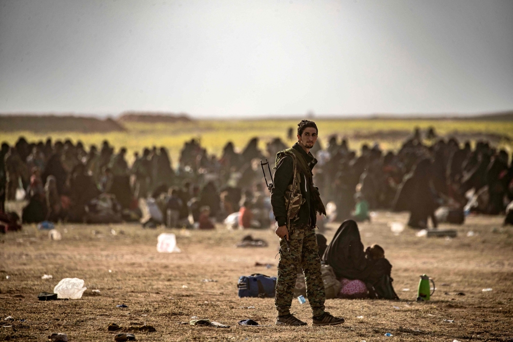 Civilians who streamed out of the Islamic State group's last Syrian stronghold sit at a screening point for new arrivals run by US-backed Syrian Democratic Forces outside Baghouz in the eastern Syrian Deir Ezzor province on March 5, 2019. AFP / Delil SOUL