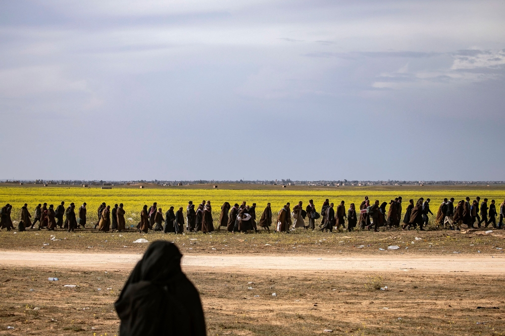 Men suspected of being Islamic State (IS) group fighters walk together towards a screening point for new arrivals run by US-backed Syrian Democratic Forces, where suspected jihadists -- many of them wounded -- were being interrogated outside Baghouz in th