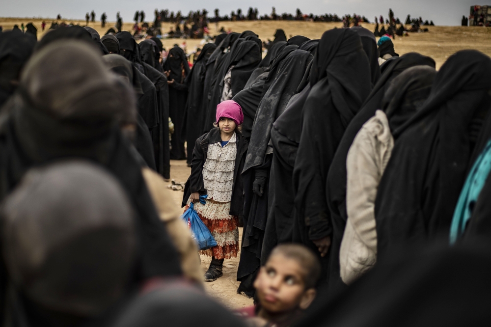 Women and children queue at a screening point as hundreds of civilians, who streamed out of the Islamic State group's last Syrian stronghold, arrive in an area run by US-backed Syrian Democratic Forces outside Baghouz in the eastern Syrian Deir Ezzor prov