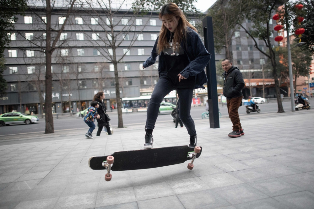 This file picture taken on February 11, 2019 shows longboarder Mu Qing flipping her board in Chengdu. / AFP / Fred DUFOUR 