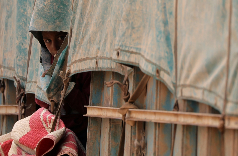 A boy looks out of a truck tarp near the village of Baghouz, Deir Al Zor province, in Syria March 7, 2019. Picture taken March 7, 2019. REUTERS/Rodi Said