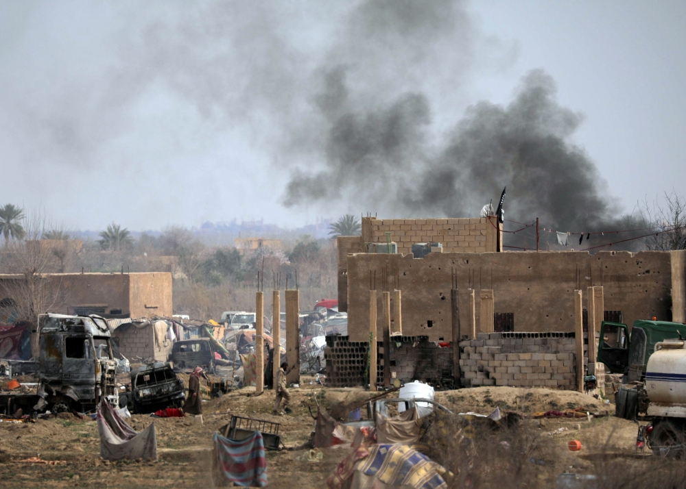 Islamic State members walk in the last besieged neighbourhood in the village of Baghouz, Deir Al Zor province, Syria March 10, 2019. REUTERS/Rodi Said