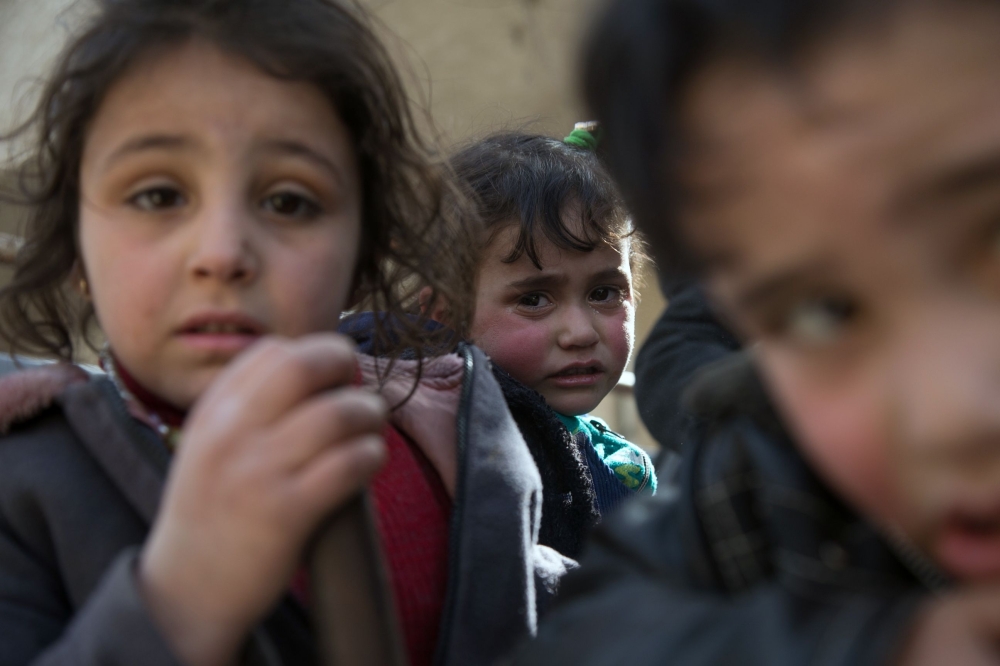 Syrian children sit in the back of a truck driven by White Helmets as they flee their homes in the town of Beit Sawa in eastern Ghouta region on March 4, 2018. AFP/Abdulmonam Eassa