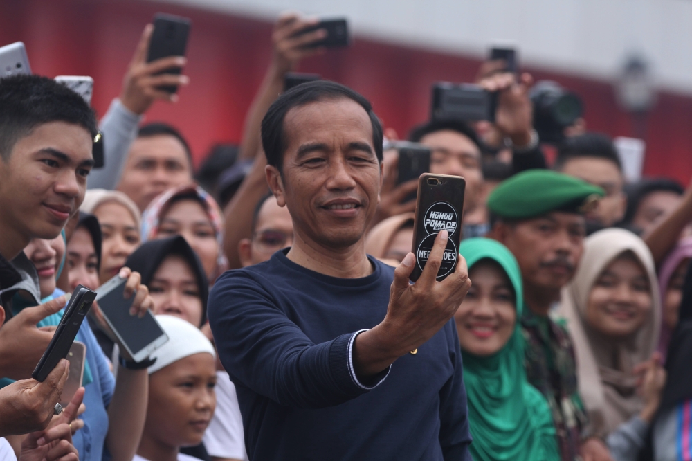 File photo of Indonesian president Joko Widodo takes a selfie as he attends the breaking the Indonesian Record Museum (MURI) in Palembang, Indonesia on March 09, 2019. A total of 500 designs Jumputan fabric with a length of 1.1 kilometers were spread out 