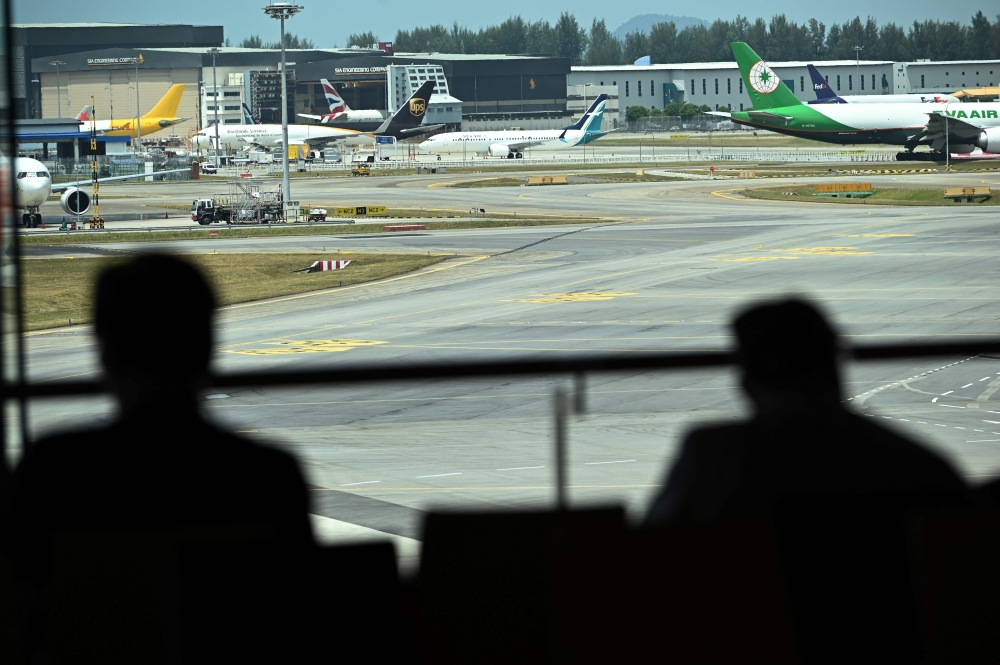Two persons look from the viewing gallery of Changi International Airport different aircrafts including a SilkAir Boeing 737 MAX aircraft (background C) parked on the airport tarmac in Singapore on March 12, 2019. AFP / Roslan RAHMAN