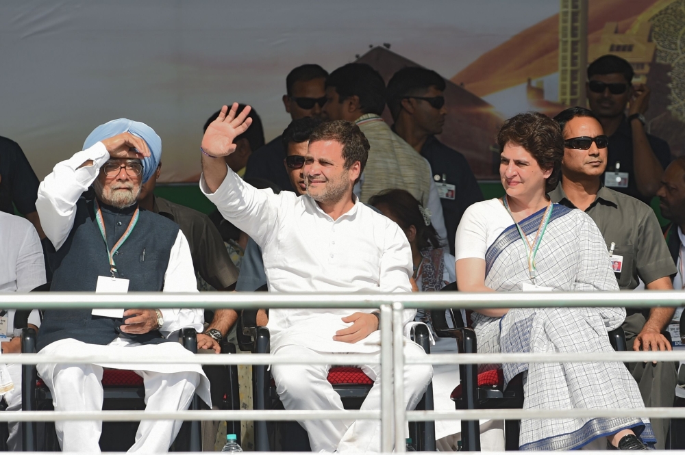 Indian Congress President Rahul Gandhi (C) waves to attendees next to All India Congress Committee general secretary for eastern Uttar Pradesh Priyanka Gandhi Vadra (R) and former Indian Prime Minister Manmohan Singh during a rally at Adalaj, some 30 kms 