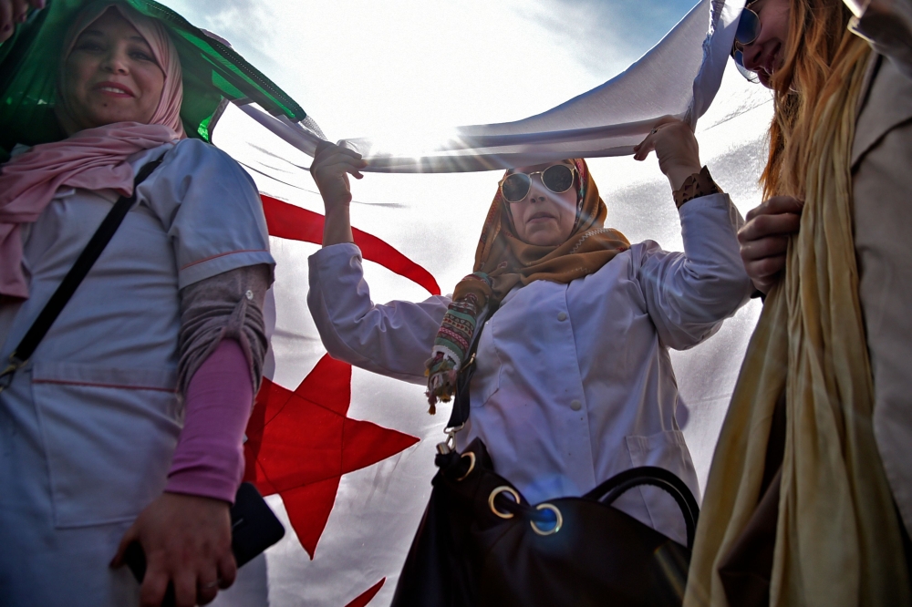 A woman holds her national flag as Algerian teachers protest in central Algiers on March 13, 2019 against President Abdelaziz Bouteflika's bid to prolong his two-decade rule. AFP / RYAD KRAMDI