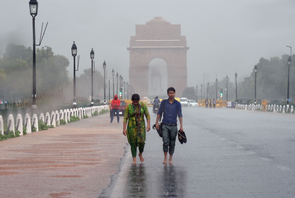 People drenched in the rain walk near India Gate during a heavy monsoon downpour in New Delhi on July 5, 2018. AFP/Prakash Singh