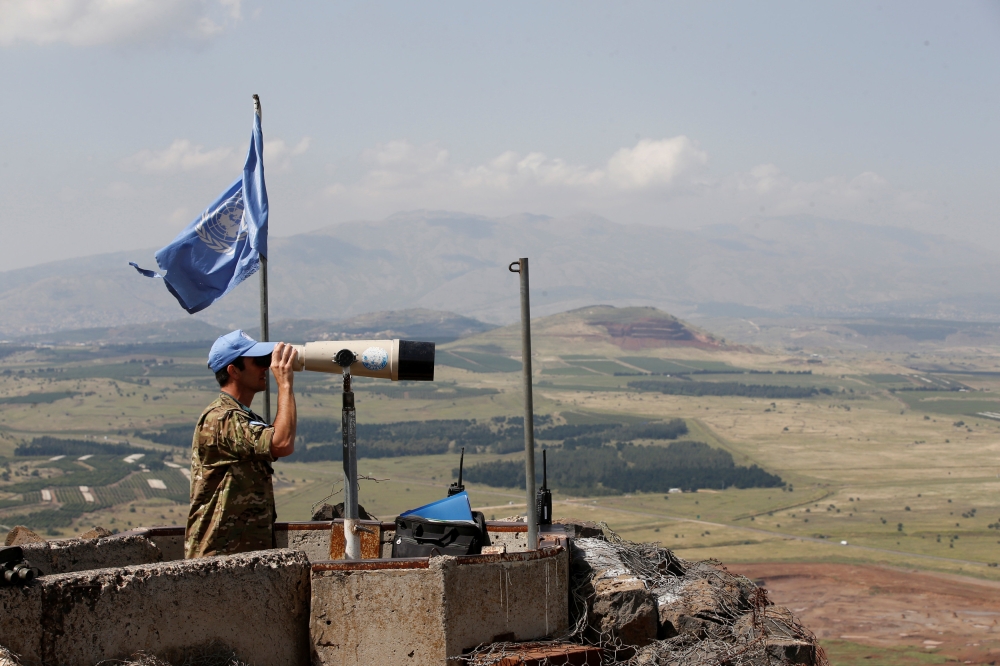 A United Nations Truce Supervision Organisation military observer uses binoculars near the border with Syria in the Israeli-occupied Golan Heights, May 11, 2018. Reuters/Baz Ratner