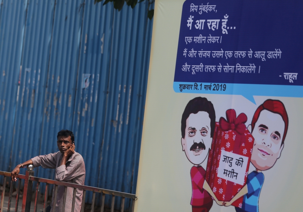 A man speaks on a phone next to a hoarding with cartoons of India's main opposition Congress Party President Rahul Gandhi and Sanjay Nirupam, President of the Mumbai Regional Congress Committee, alongside a road in Mumbai, India, February 22, 2019. REUTER