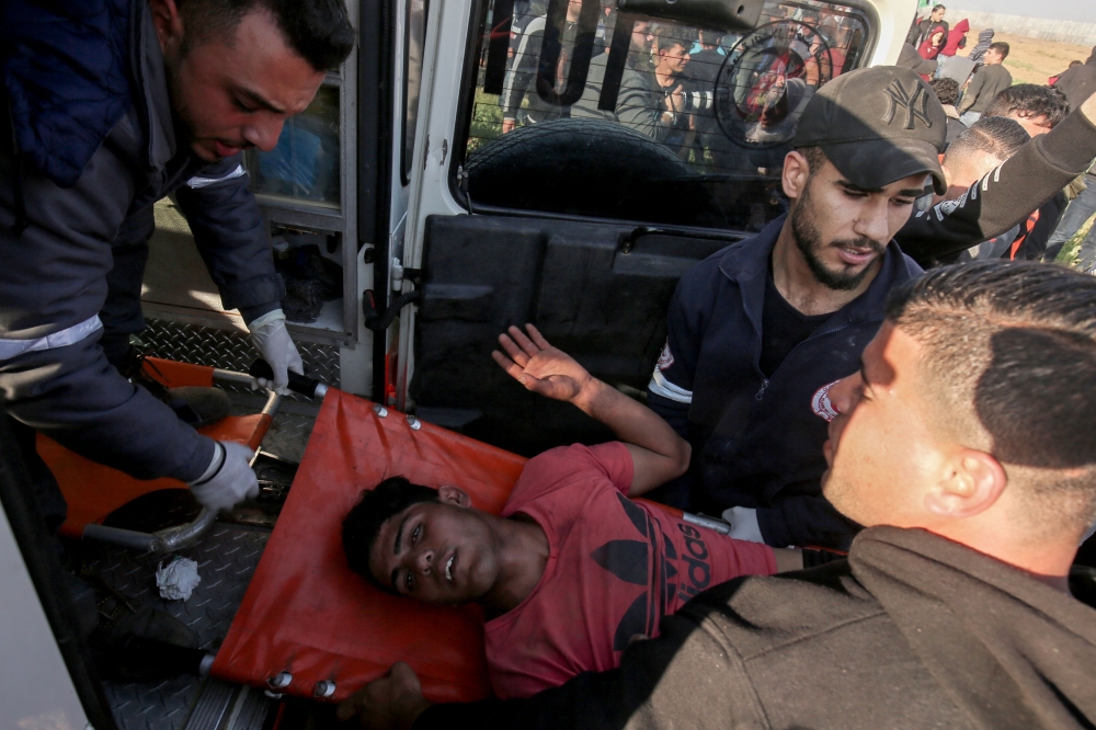 Palestinian paramedics carry an injured protester at the border fence with Israel east of Gaza City on March 22, 2019. AFP / Said Khatib 