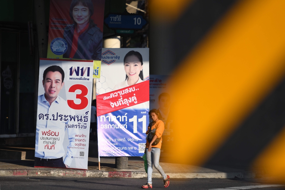 A woman walks past electoral posters displayed along a road in Bangkok on March 23, 2019, on the eve of the general election. Thais will head to polls on March 24 for a highly anticipated election -- the first since the junta wrested power in a 2014 coup.