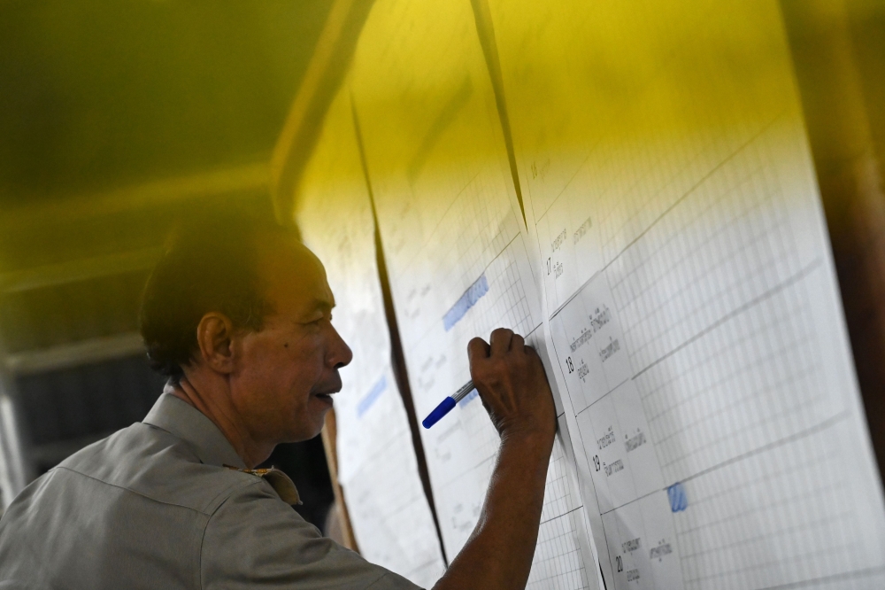 An electoral official tallies the vote count at a polling station in Bangkok on March 24, 2019 after polls closed in Thailand's general election. / AFP / Ye Aung THU