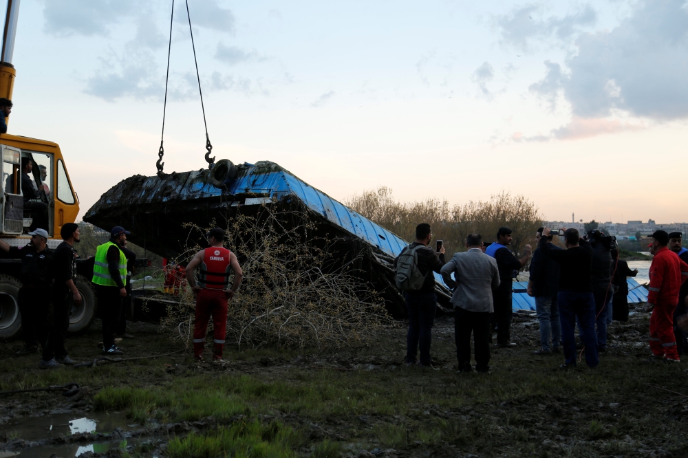Members of the Iraqi Civil Defence rescue team lift a ferry which sank in the Tigris River with a crane in Mosul, Iraq March, 23, 2019. Picture taken March 23, 2019. REUTERS