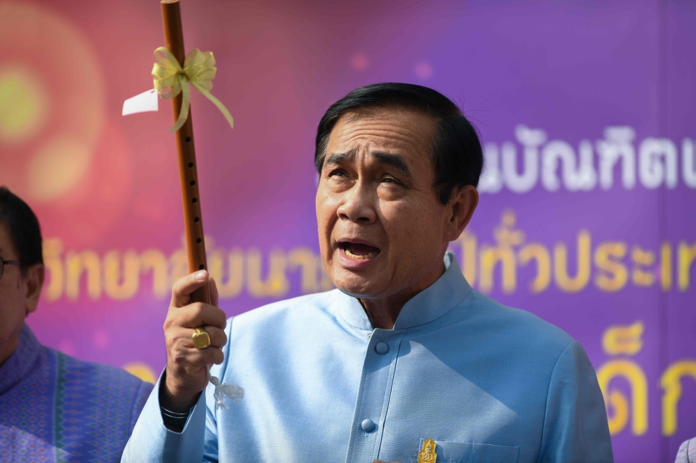 Thailand's Prime Minister Prayut Chan-O-Cha holds up a a traditional flute as he arrives at the Government House for a cabinet meeting in Bangkok on March 26, 2019, two days after the country's general election. / AFP / Ye Aung THU 