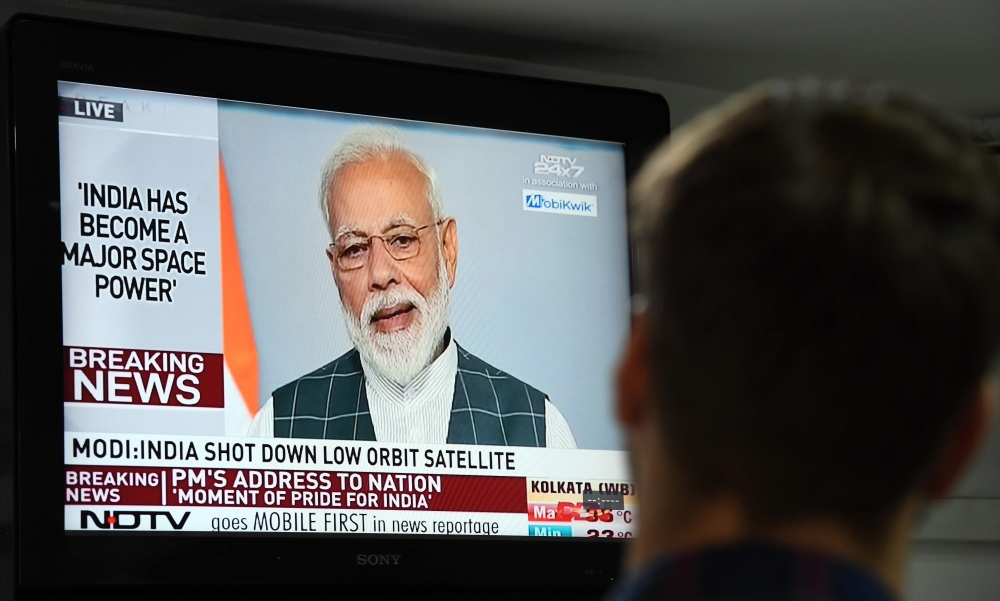 A man watches Indian Prime Minister Narendra Modi's address to the nation on a local news channel in New Delhi on March 27, 2019. AFP / Prakash SINGH