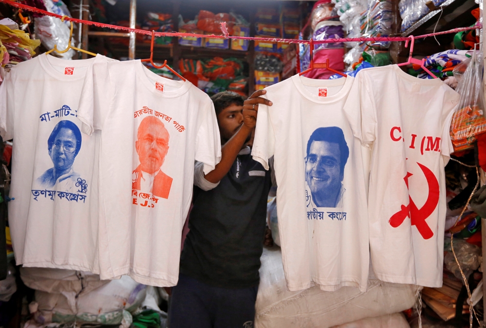 A worker displays T-shirts with images of (L-R) Chief Minister of West Bengal state Mamata Banerjee, Prime Minister Narendra Modi, India's main opposition Congress party Chief Rahul Gandhi and logo of Communist Party of India (Marxist) CPI (M), for sale i