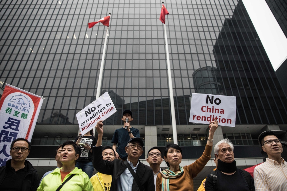 Hong Kong pro-democracy legislator Claudia Mo (centre R) and bookseller Lam Wing-kee (centre L) display placards outside the government headquarters during a rally in Hong Kong on March 31, 2019 to protest against the government's plans to approve extradi