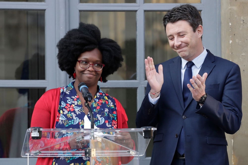 Newly appointed French Junior Minister and Government's spokesperson Sibeth Ndiaye (L) is applauded by her predecessor Benjamin Griveaux after delivering a speech during a hand over ceremony at the ministry in Paris on April 1, 2019. / AFP / Thomas SAMSON
