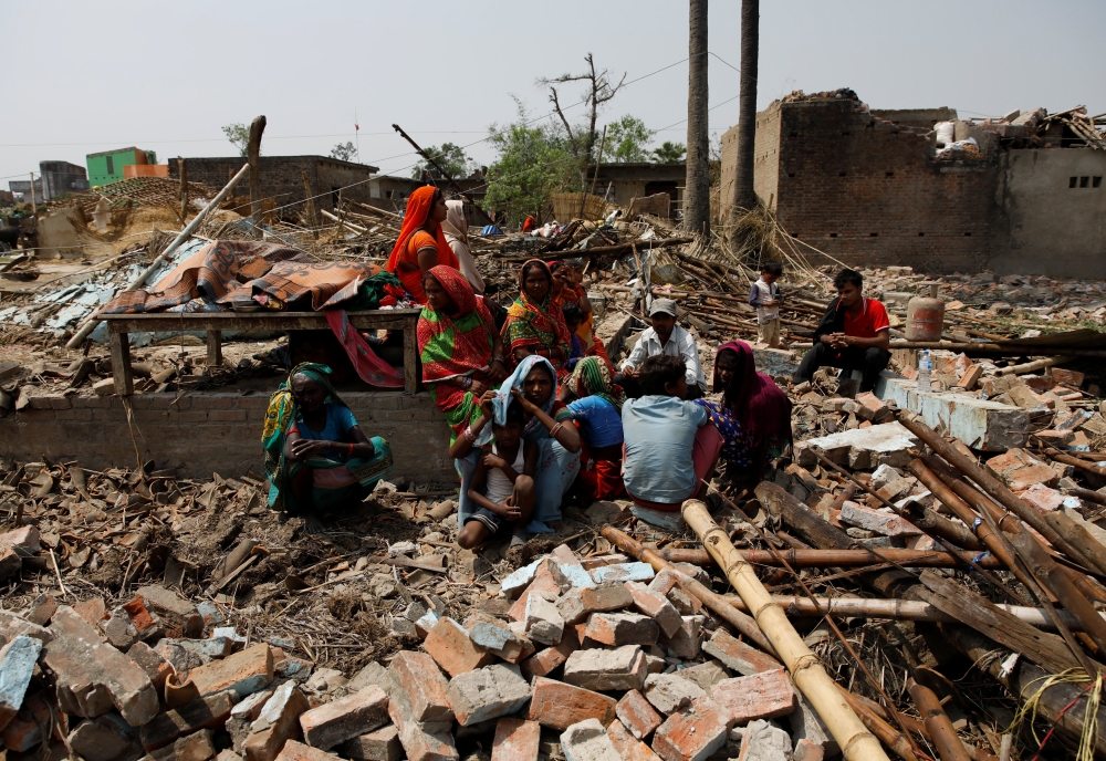 People sit on the rubbles of the houses destroyed by a storm at Bara district, Nepal April 1, 2019. REUTERS/Navesh Chitrakar