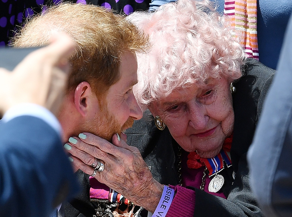 (FILES) In this file photo taken on October 16, 2018, Britain's Prince Harry hugs 98-year old war widow Daphne Dunn as he walks outside the Sydney’s Opera House to meet people. AFP / SAEED KHAN