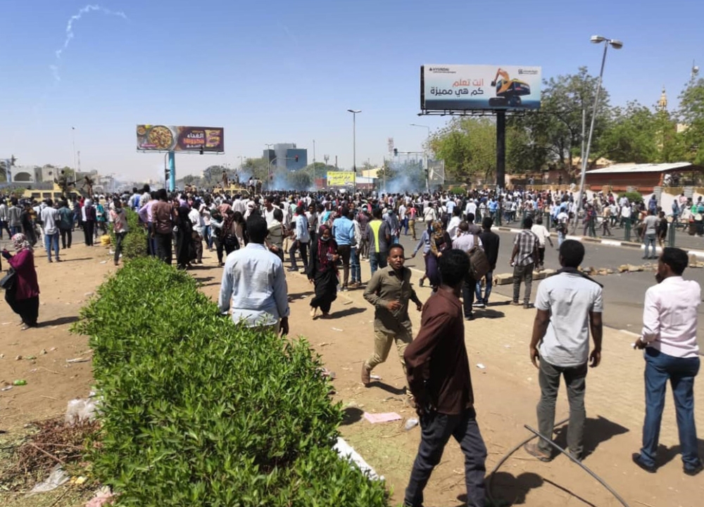 Sudanese protesters run for cover from teargas outside the military headquarters in the capital Khartoum on April 7, 2019.  AFP 