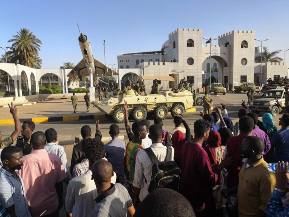 Sudanese protesters flash the victory sign at a passing military vehicle as they gather for a second day outside the military headquarters in the capital Khartoum on April 7, 2019. AFP / -
