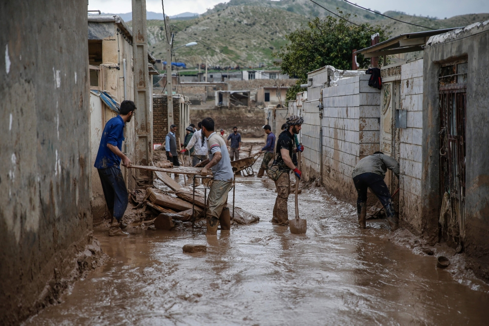 Men clear away mud following floods in the Iranian city of Mamulan in Lorestan province on April 7, 2019.  AFP / HOSSEIN MERSADI
