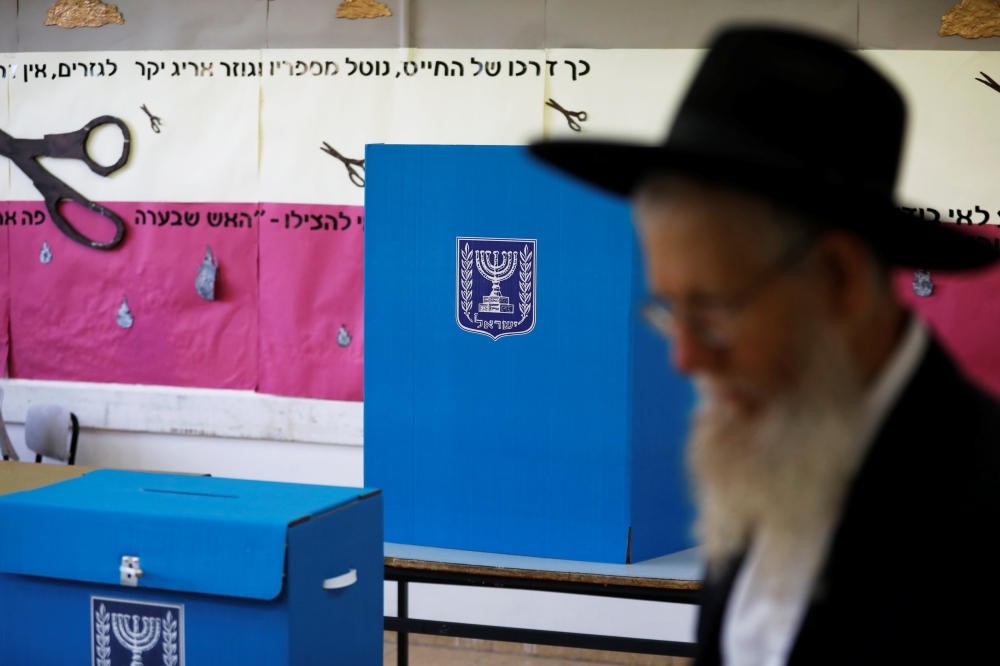 A man walks next to a voting booth and ballot box at a polling station as Israelis vote in a parliamentary election, in Jerusalem April 9, 2019. REUTERS/Ronen Zvulun