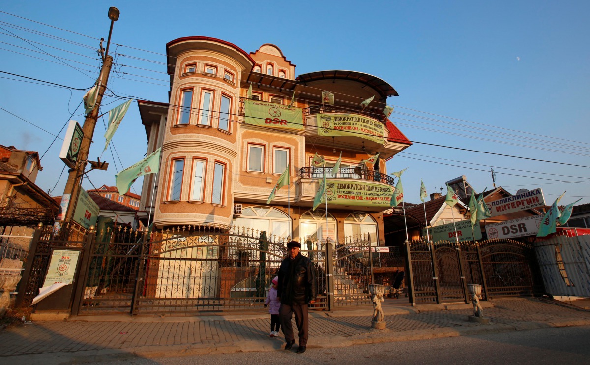 A man walks next to a house decorated with party flags in Suto Orizari, a district with Europes largest Roma communities, Macedonia, December 7, 2016. Thomson Reuters Foundation/Ognen Teofilovski