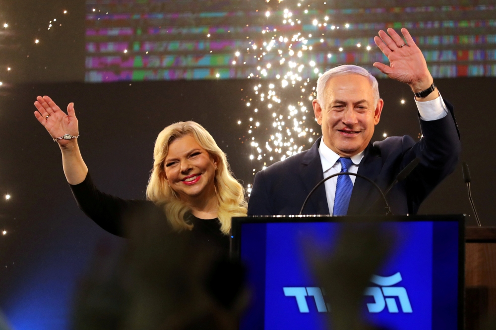 Israeli Prime Minister Benjamin Netanyahu and his wife Sara wave as Netanyahu speaks following the announcement of exit polls in Israel's parliamentary election at the party headquarters in Tel Aviv, Israel April 10, 2019. REUTERS/Ammar Awad