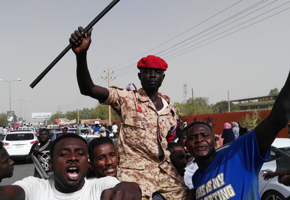 Sudanese men chant slogans along with a soldier in the capital Khartoum. (AFP)