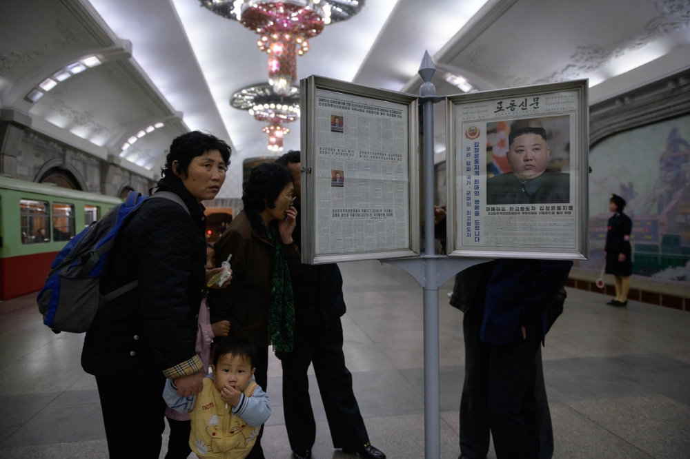 Commuters look at a copy of the Rodong Sinmun newspaper showing an image of North Korea's leader Kim Jong Un, at a newstand in a subway station in Pyongyang on April 13, 2019. AFP / Ed JONES
