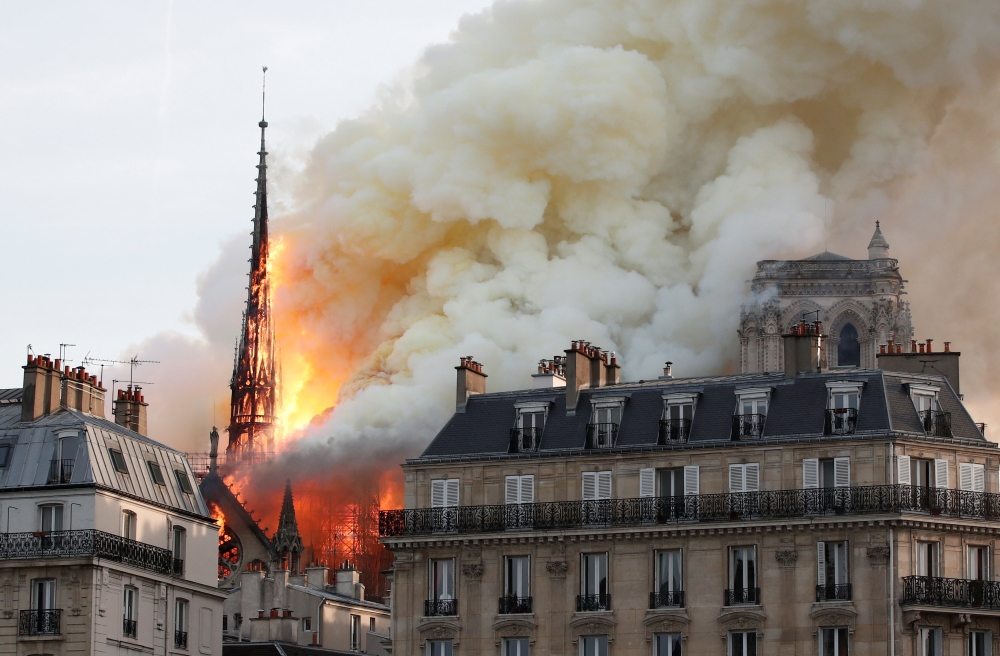 Smoke billows as fire engulfs the spire of Notre Dame Cathedral in Paris, France April 15, 2019. REUTERS/Benoit Tessier
