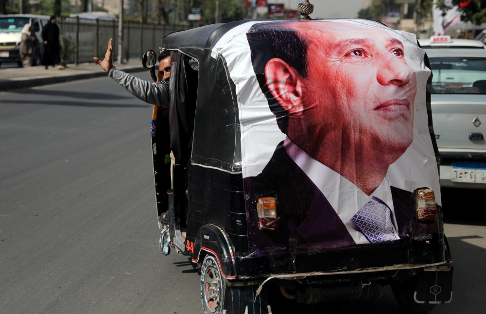 A man gestures as he rides a motorized vehicle showing a poster of Egyptian President Abdel Fattah al-Sisi in Cairo, Egypt, March 27, 2018. Reuters/Ammar Awad