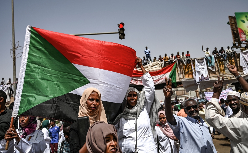 Sudanese protestors wave national flags and shout slogans as people continue to protest outside the army complex in the capital Khartoum on April 17, 2019.  AFP / OZAN KOSE