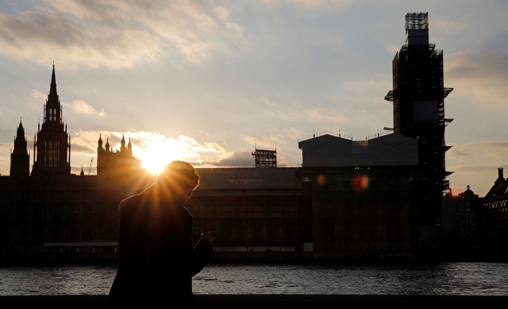 A man stands on the banks of River Thames across from the Houses of Parliament in Westminster in central London on March 27, 2019. AFP/Tolga Akmen