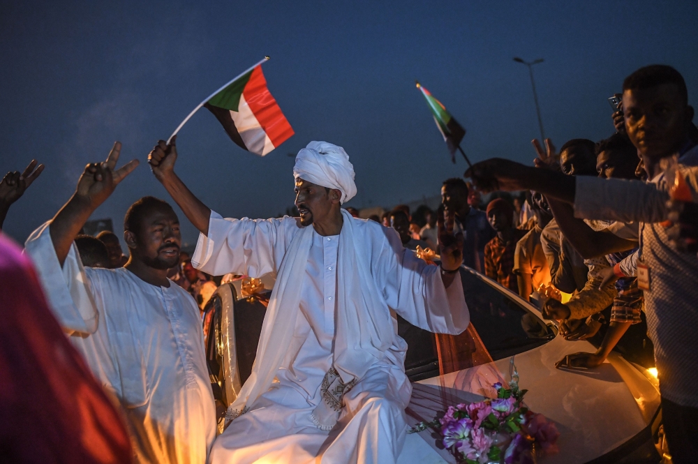 A Sudanese bridegroom waves a Sudan national flag on a wedding car during a protest outside the army complex in the capital Khartoum on April 20, 2019. AFP / OZAN KOSE