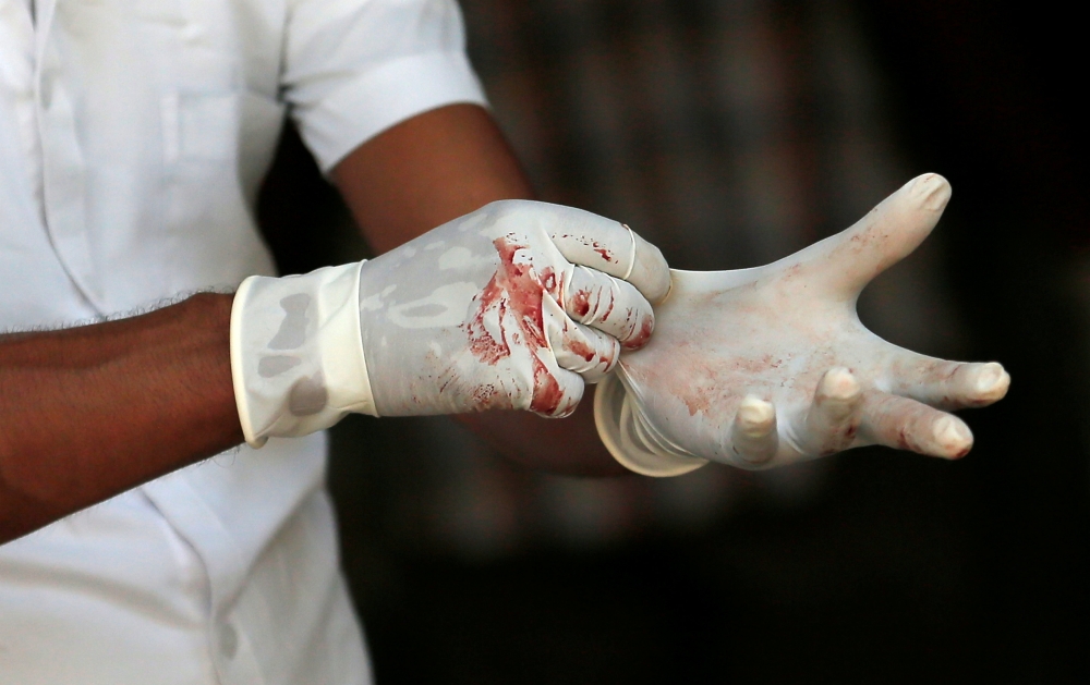 Blood on gloves of a police mortuary official is seen as he waits for casualties after an explosion at St. Anthony's Shrine, Kochchikade church in Colombo, Sri Lanka April 21, 2019. Reuters/Dinuka Liyanawatte