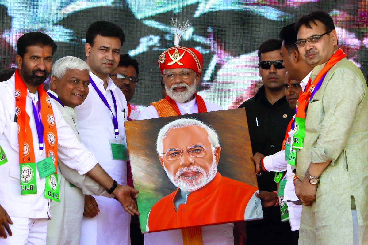 Indian Prime Minister Narendra Modi (C) holds a canvas displaying a portrait of himself during his election rally in Chittorgarh, in the western state of Rajasthan, on April 21, 2019. / AFP / Himanshu Sharma