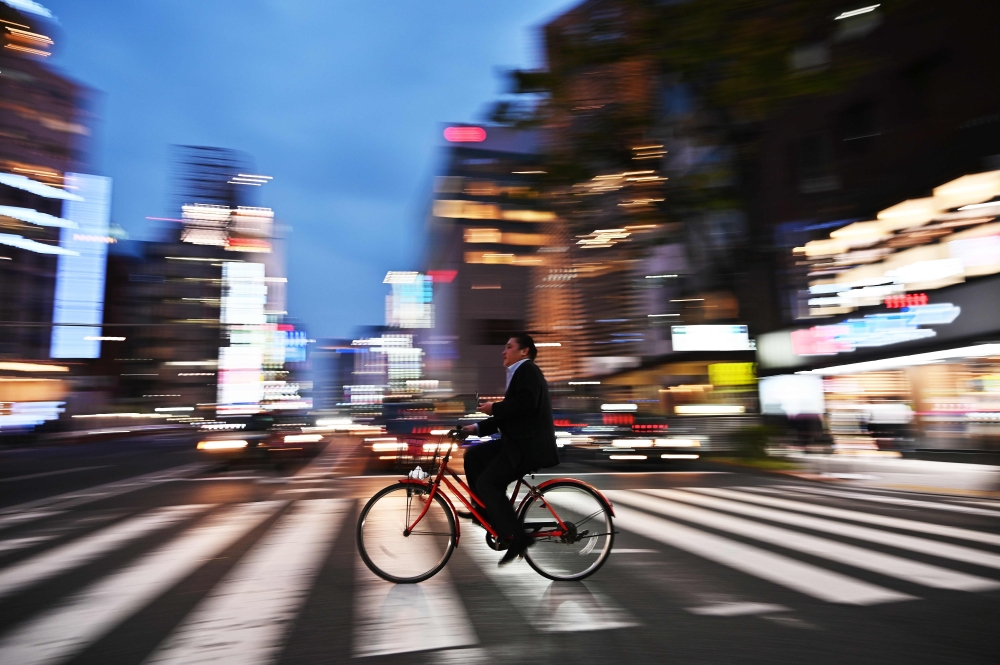 A man rides his bicycle at night in Tokyo on April 22, 2019. AFP/Charly Triballeau
 