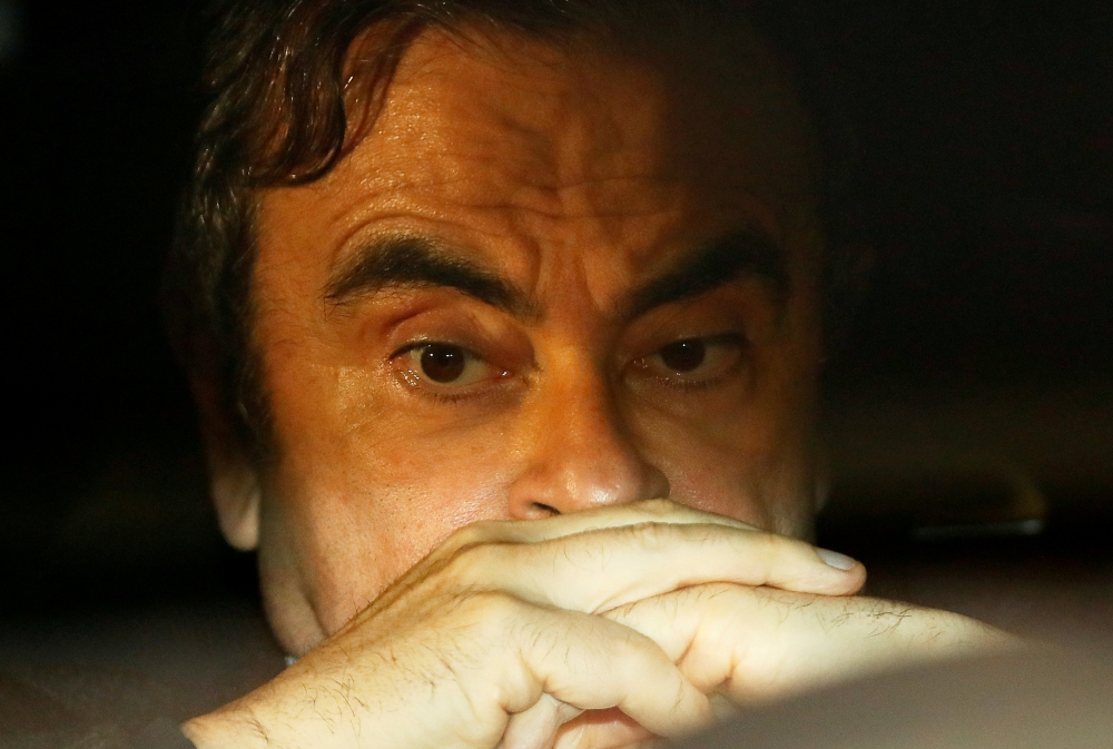FILE PHOTO : Former Nissan Motor Chairman Carlos Ghosn sits inside a car as he leaves his lawyer's office after being released on bail from Tokyo Detention House, in Tokyo, Japan, March 6, 2019. REUTERS/Issei Kato