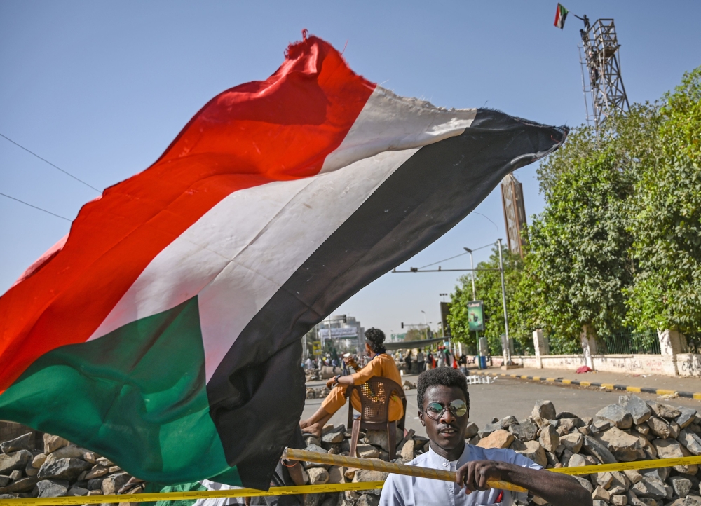 A Sudanese protesterr waves a national flag near a makeshift barricade during an a sit-in outside the army headquarters in the capital Khartoum on April 30, 2019.  AFP / OZAN KOSE