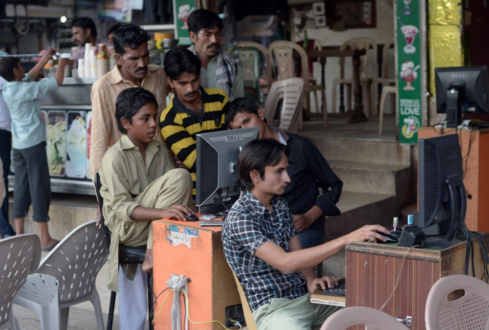 In this file photo taken on May 9, 2014 Pakistani vendors use computers to upload music and video files onto their client's mobile phones at a market in Faisalabad. AFP / Farooq Naeem